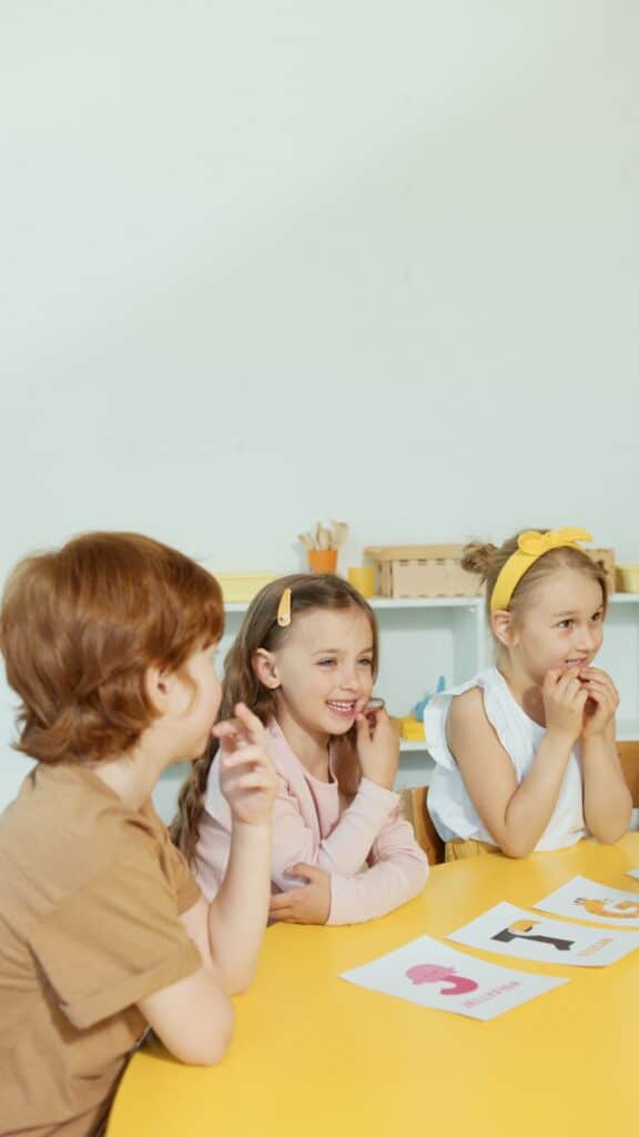 bambini introno ad un tavolo che giocano con delle lettere