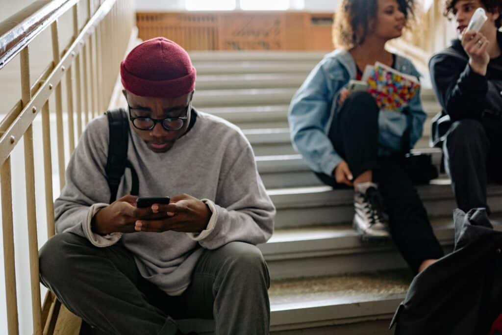 giovane ragazzo che scrolla i social sulle scale